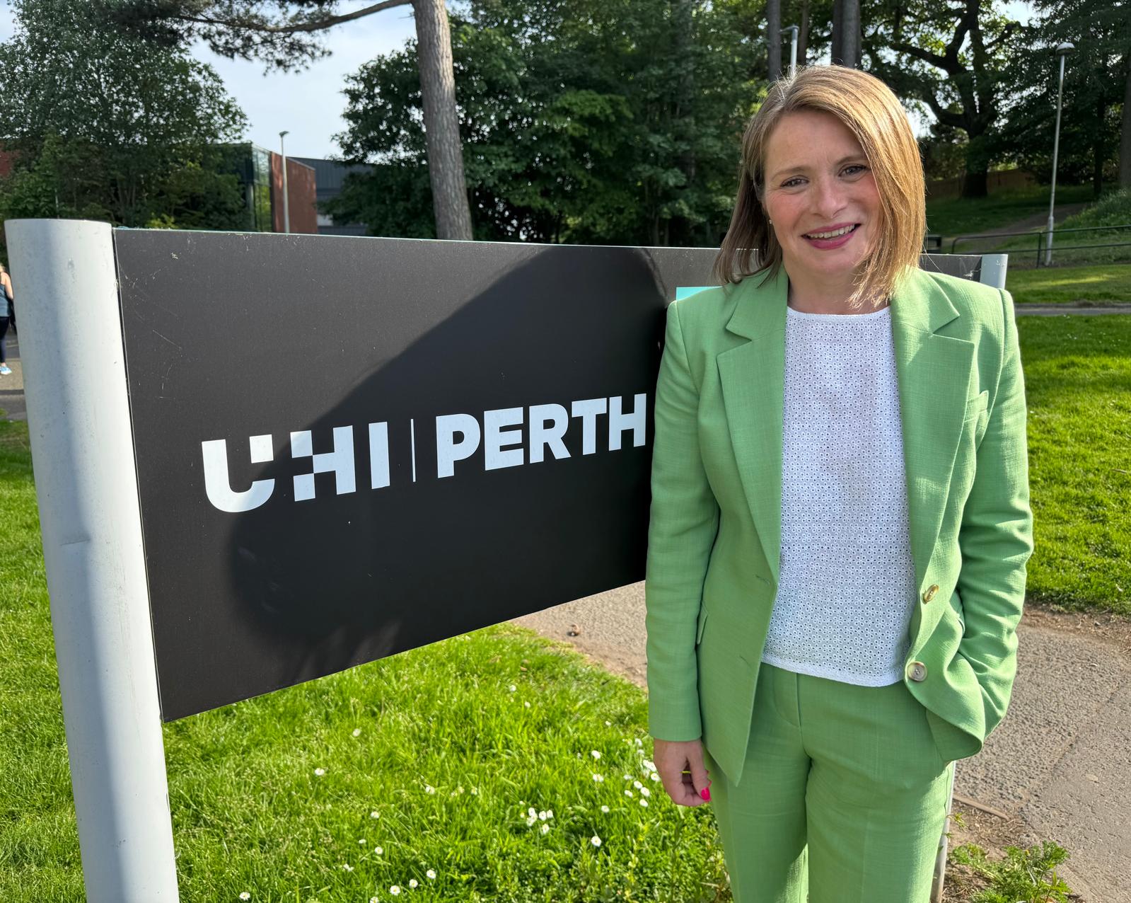 Justine beside the UHI Perth campus sign